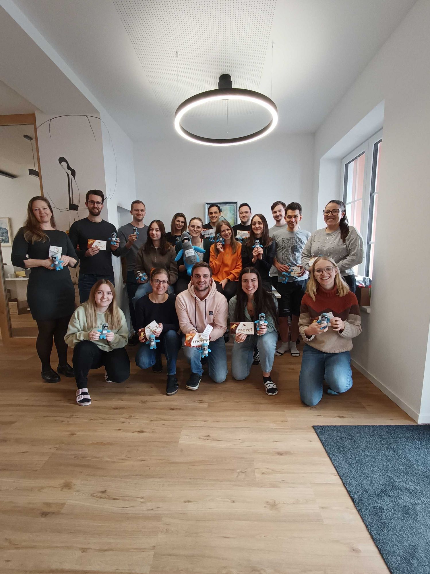 The WS team members present the personalised gift from Fischis Ski School and hold the chocolate bars and Fischis key rings in their hands with a smile.