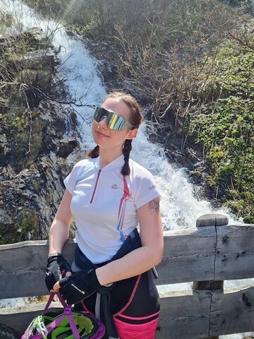 Michelle Rottensteiner im Raddress mit Sonnenbrille und Helm vor einem Wasserfall