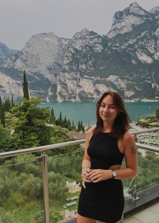 Michelle Rottensteiner steht auf einem Balkon mit Blick auf einen See und Berge