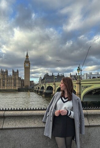 Michelle Rottensteiner blickt über ihre Schultern auf die Themse in London, im Hintergrund die London Bridge und Big Ben