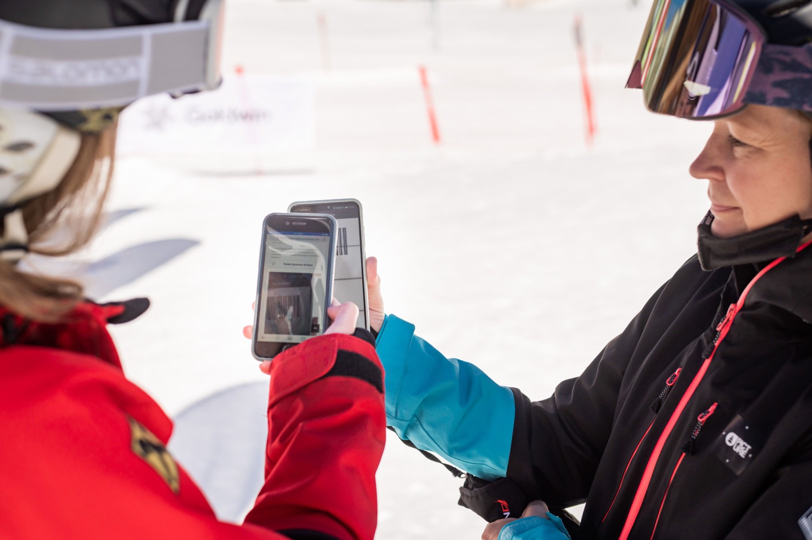 Skilehrerin scannt digitales Ticket von Gast mit Smartphone