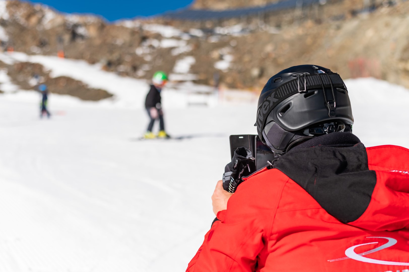 Skilehrer filmt Kinder beim Skifahren
